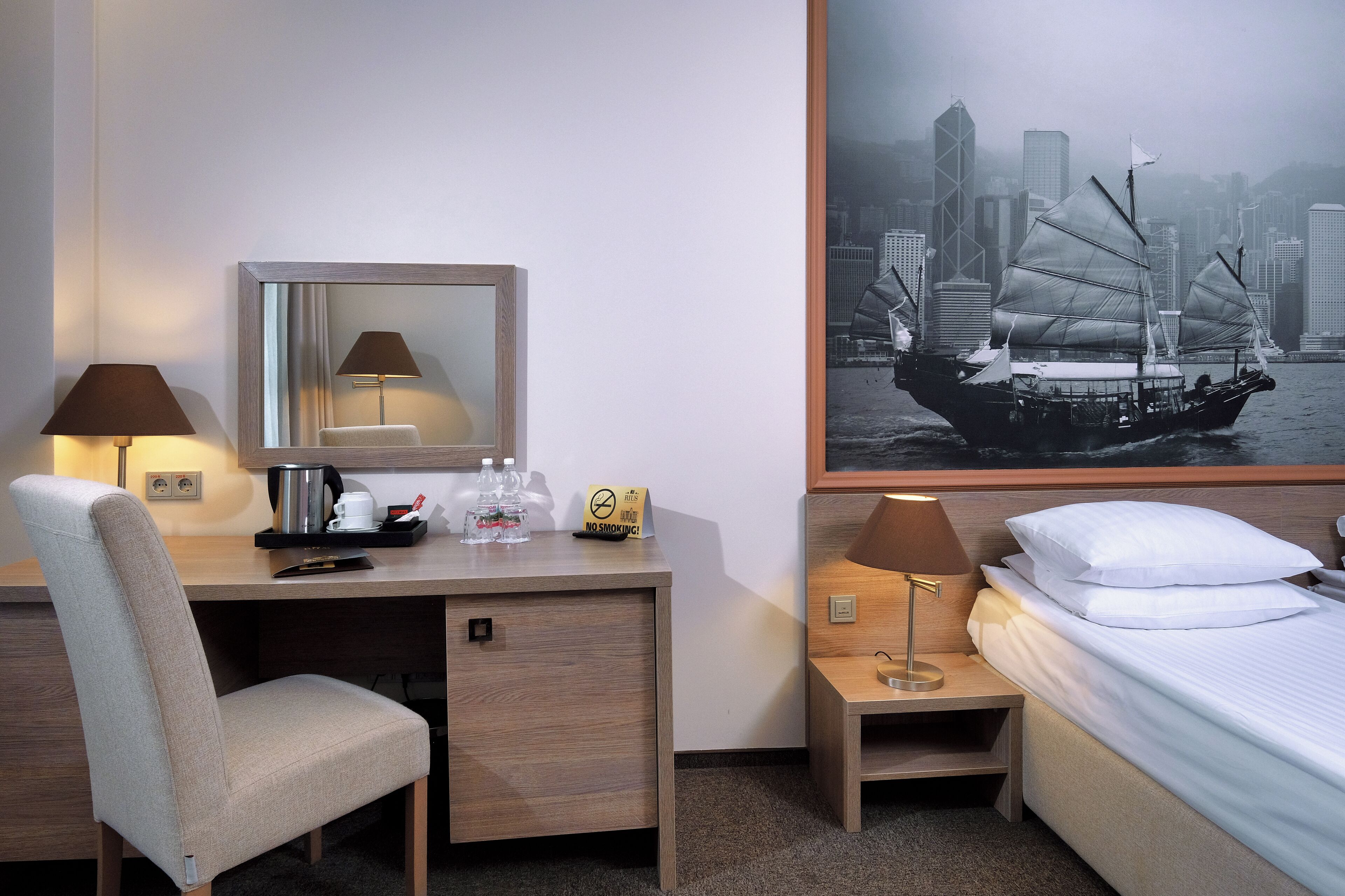 Une chambre d’hôtel équipée d’un bureau, d’une chaise, d’une table de chevet, d’une lampe et d’un lit.