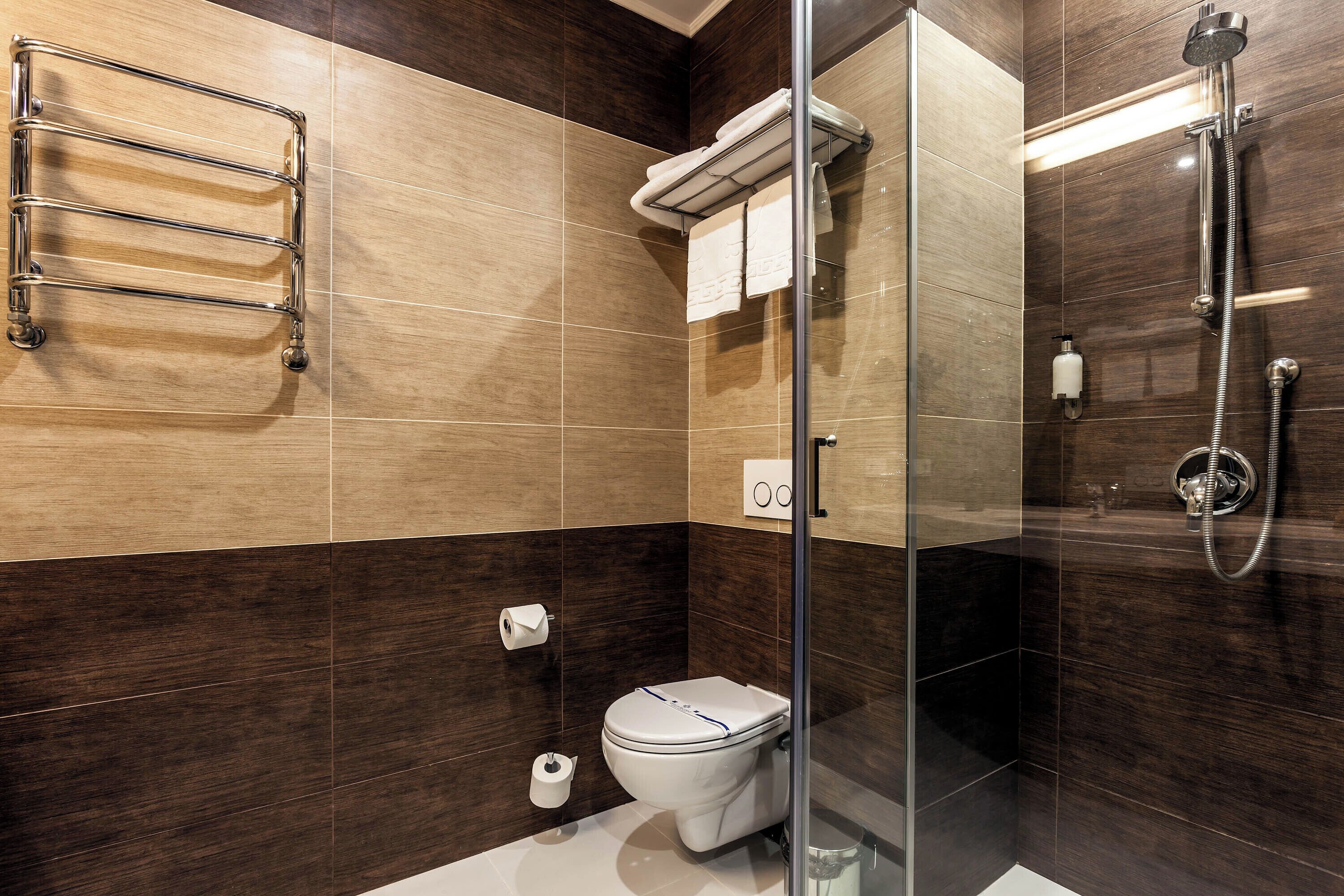 Un baño moderno con cabina de ducha de vidrio, inodoro blanco y perchero.