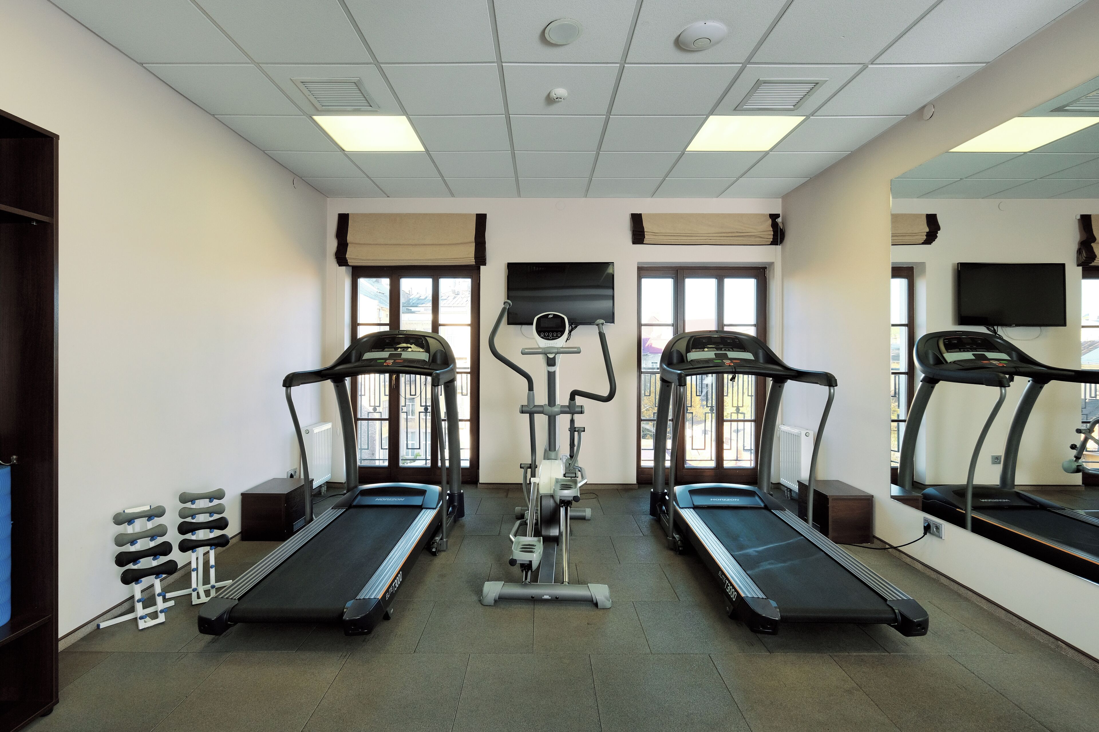 Une salle de sport équipée de deux tapis de course, d’un vélo elliptique et d’appareils de musculation.