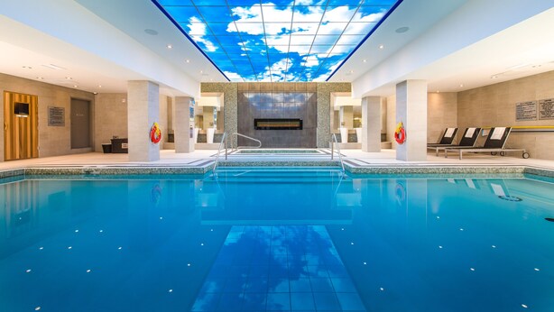 A large indoor swimming pool with a ceiling that simulates a blue sky with clouds. - Delta Hotels by Marriott Waterloo (Waterloo)