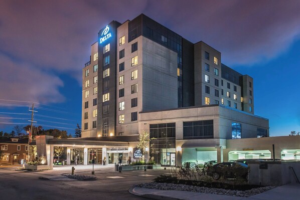 A multi-story hotel with a prominent 'Delta' sign, a covered entrance, and a parking area.