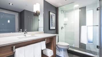 A modern bathroom with a glass shower enclosure, a wooden vanity, and a large mirror.