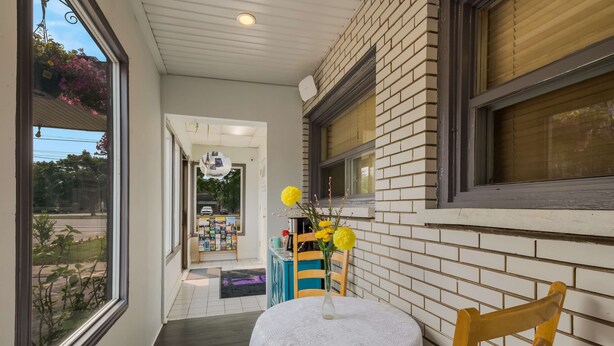 A cozy room with a small table and chair, a window with a view of the street, and a brick wall. - Knights Inn Burlington, ON (Burlington)