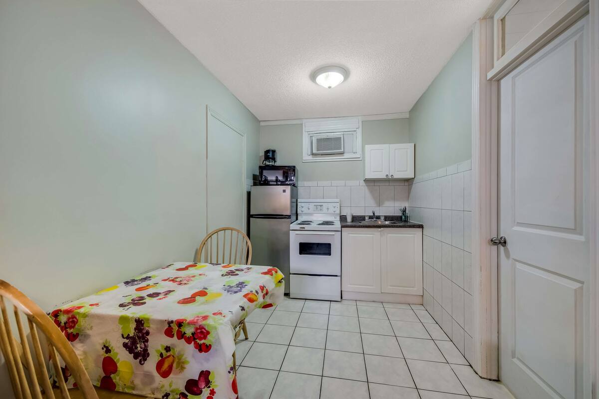 A compact kitchen with a dining table, chairs, a refrigerator, a microwave, and a stove.