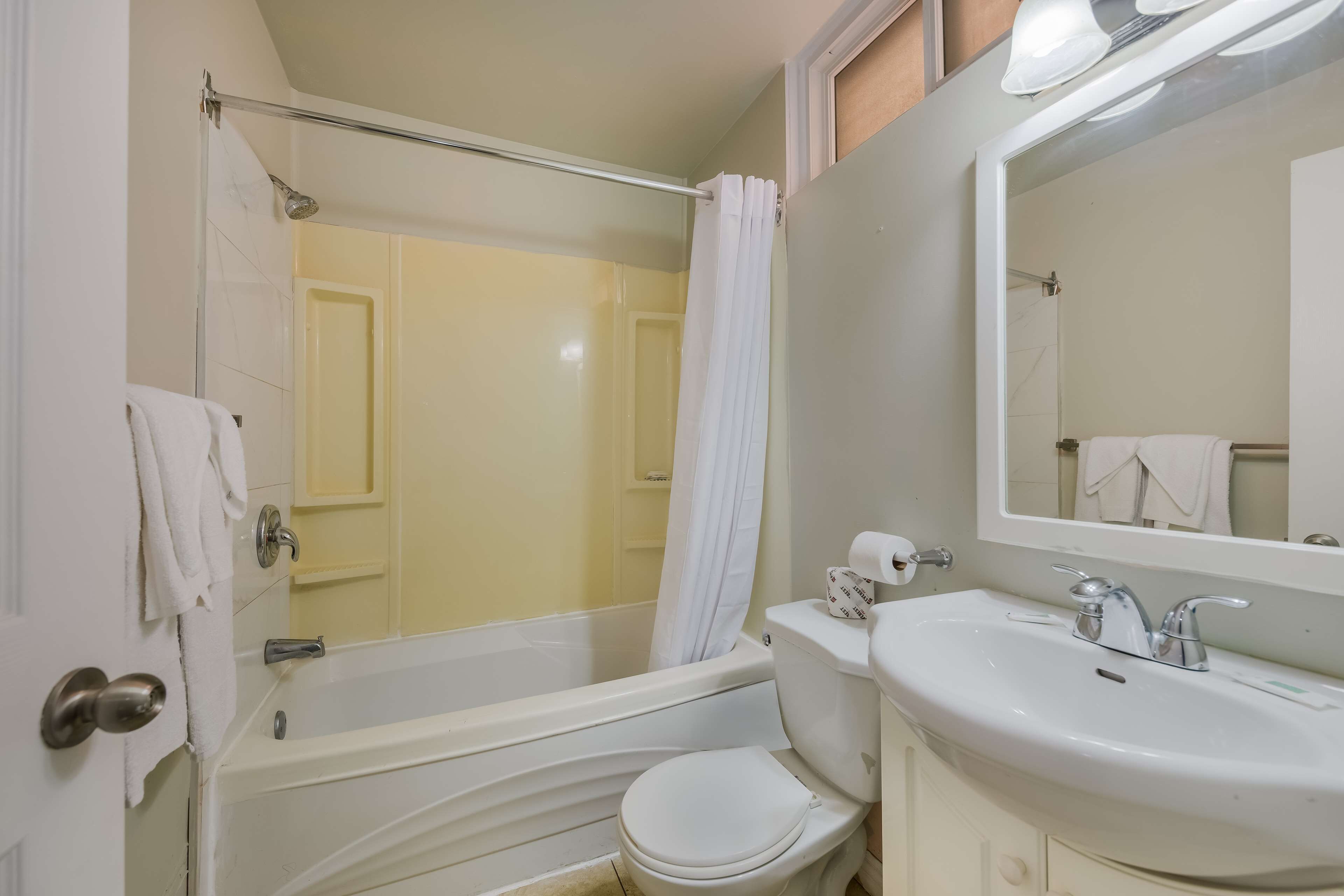 A bathroom with a bathtub, toilet, sink, and a mirror.