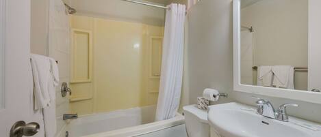 A bathroom with a bathtub, toilet, sink, and a mirror.
