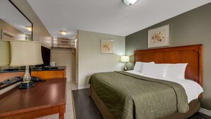 A hotel room with a bed, a desk, a lamp, and a mirror. - Knights Inn Burlington, ON (Burlington)