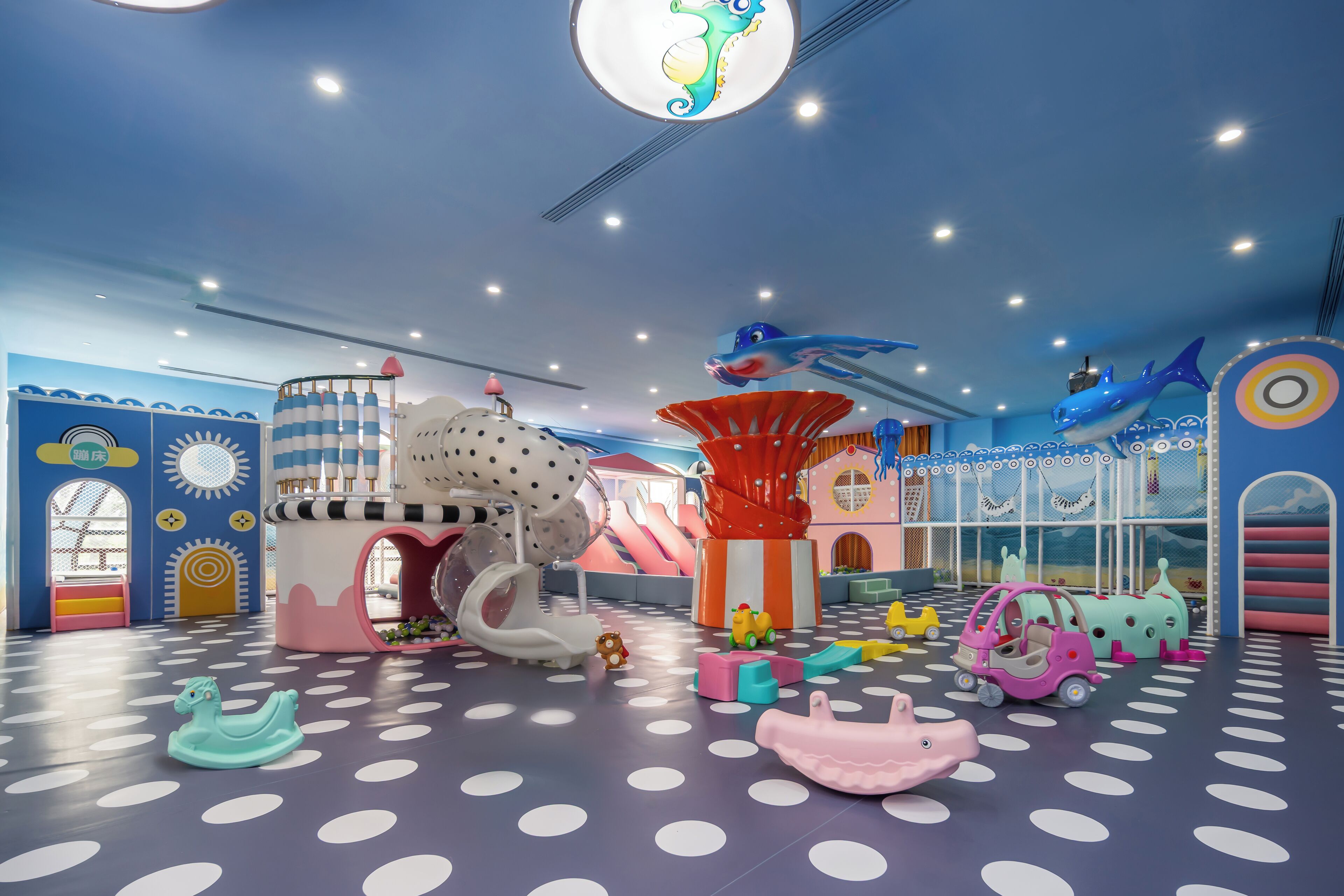Un espace de jeux pour enfants avec des toboggans, des structures d’escalade et divers véhicules ludiques.