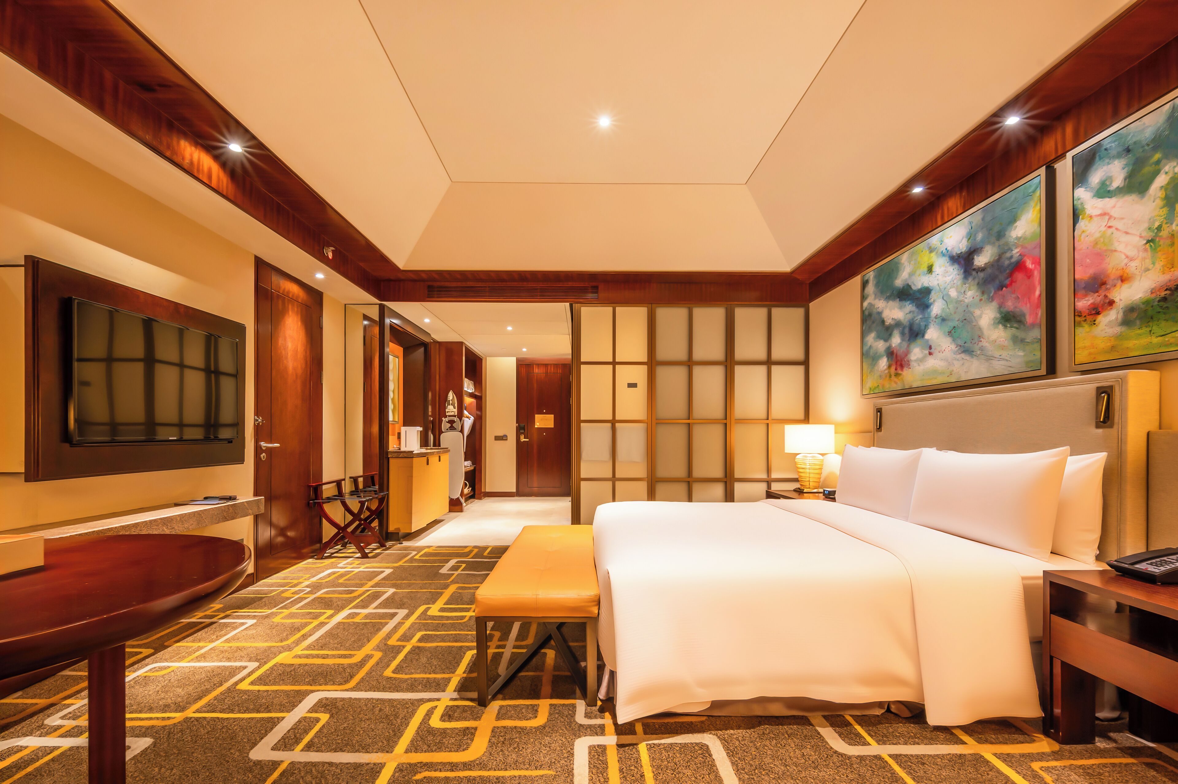 A hotel room with a large bed, a desk, a TV, and a seating area.