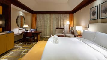 Una habitación de hotel con una cama grande, un escritorio, una silla, un televisor y un baño.