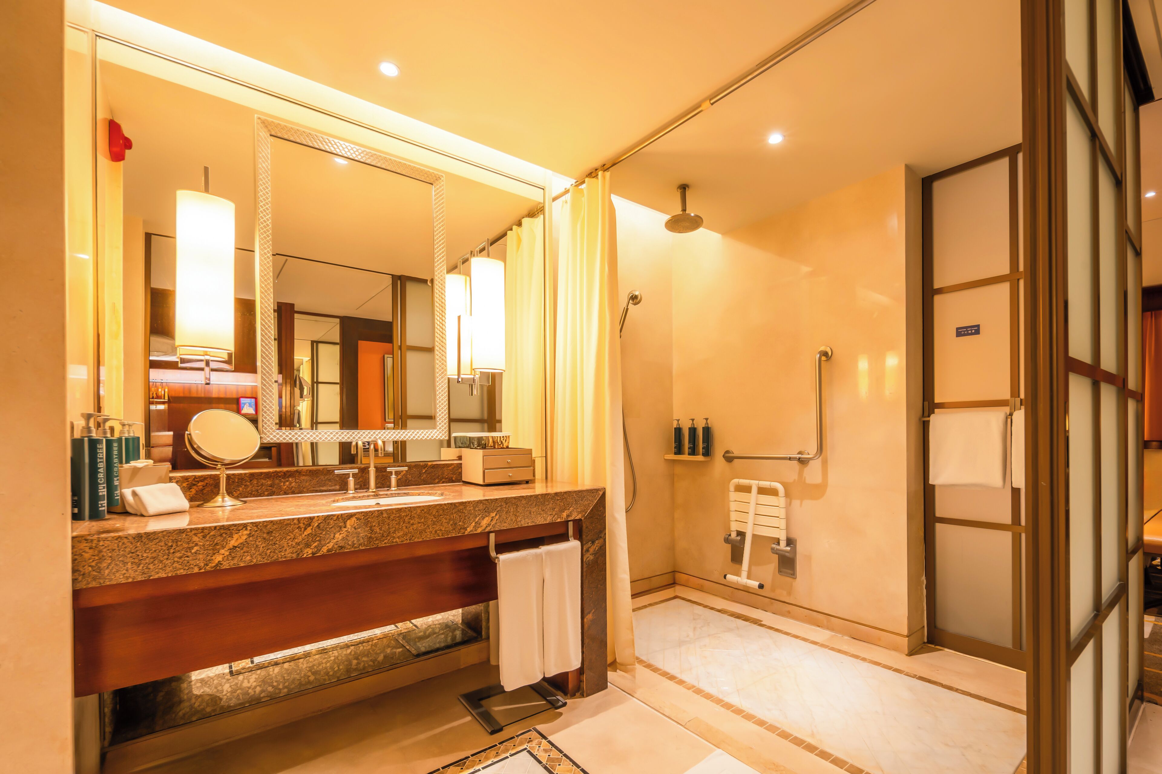 A modern bathroom with a granite countertop, a large mirror, a shower with a glass door, and a towel rack.