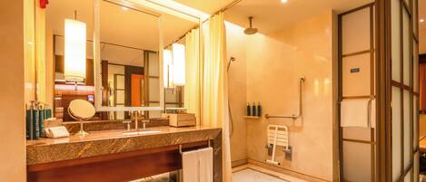 A modern bathroom with a granite countertop, a large mirror, a shower with a glass door, and a towel rack.