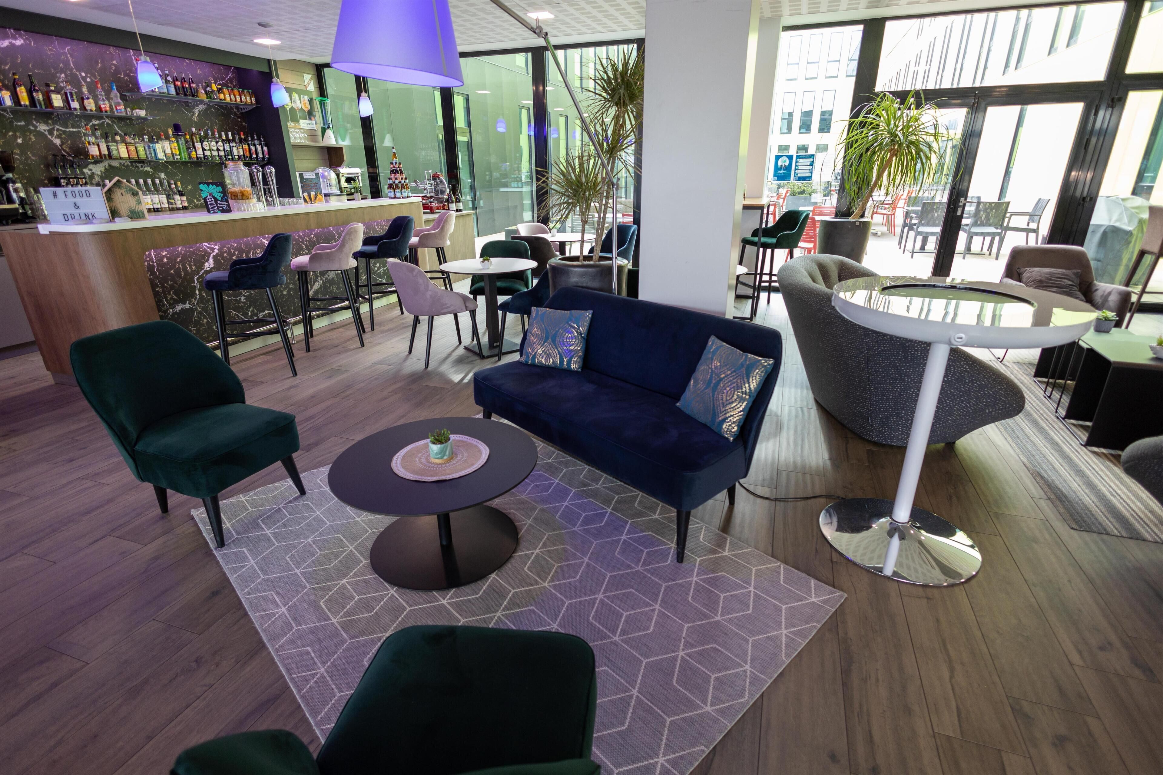 A modern lounge area with seating, a bar, and large windows.