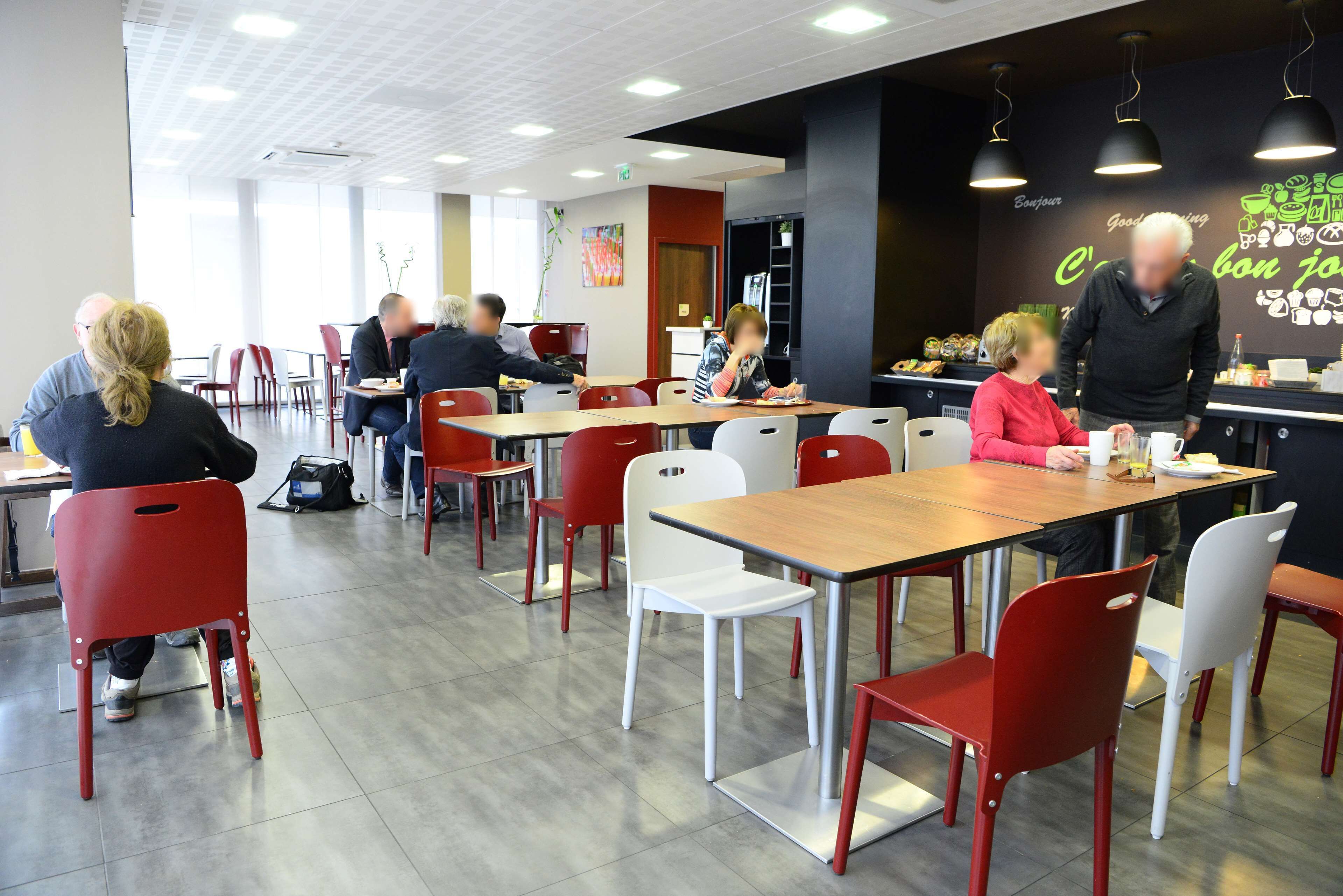 A modern dining area with red and white chairs, tables, and a black counter with a menu.