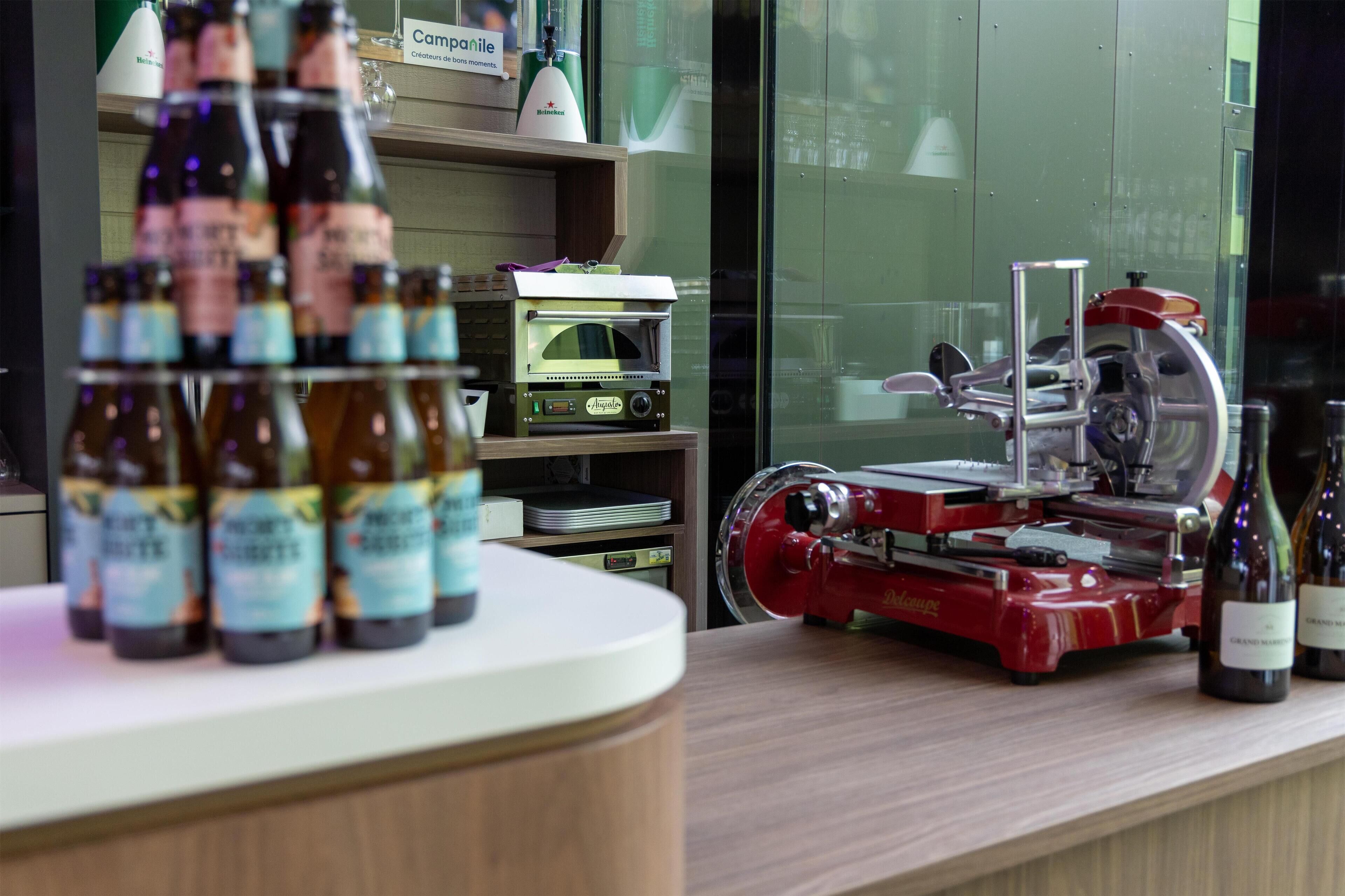 Zona de bar con botellas de cerveza y un equipo rojo, posiblemente una licuadora o mezcladora, sobre una barra.
