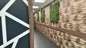 A hallway with a geometric wall design, a wooden panel, and a green wall with vertical gardens. - Campanile Belfort Montbéliard - Gare La Jonxion (Meroux-Moval)
