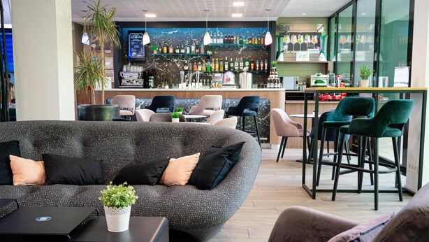 A modern lounge area with a sofa, armchairs, and a bar with a marble backsplash. - Campanile Belfort Montbéliard - Gare La Jonxion (Meroux-Moval)