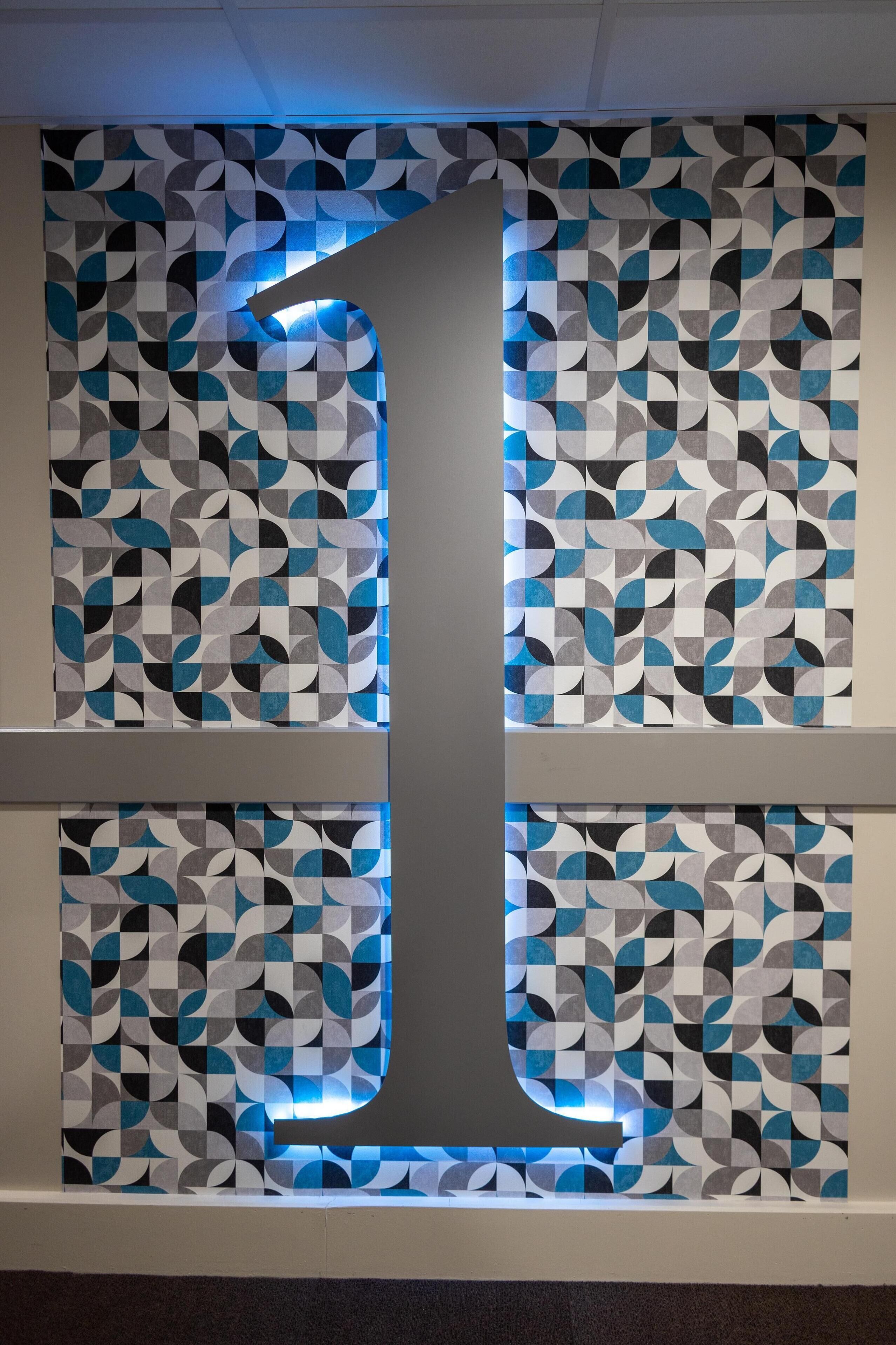 A wall with a geometric pattern and a large illuminated number '1'.
