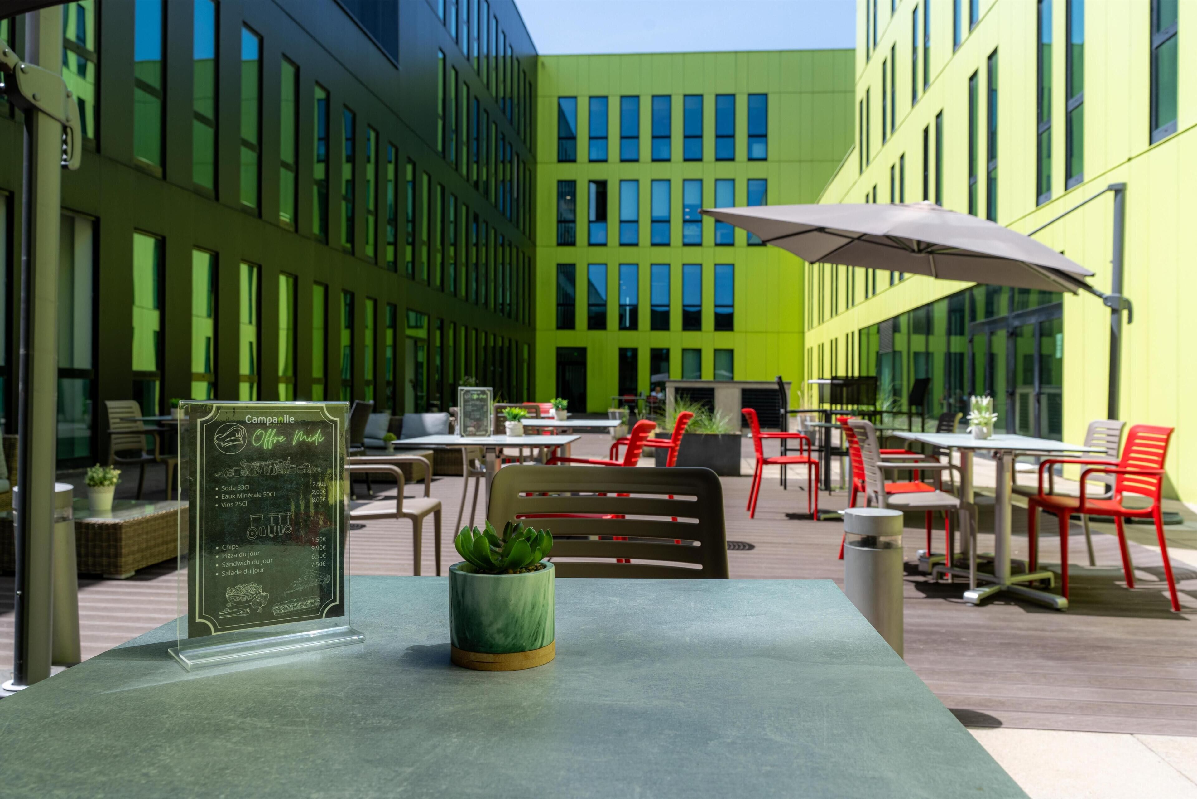 An outdoor cafe area with tables, chairs, and a menu board.