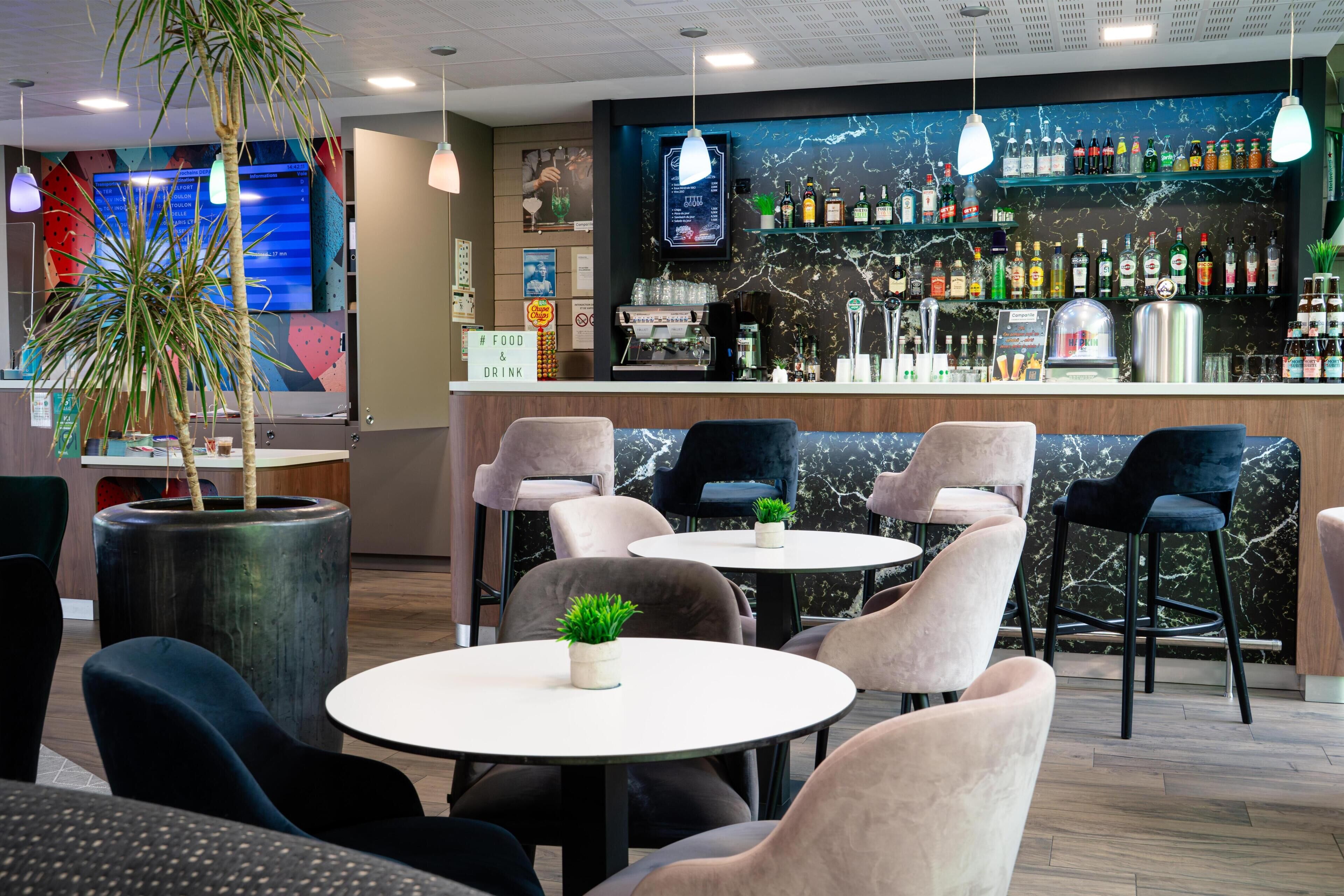 A bar area with multiple seating options, including round tables and bar stools.