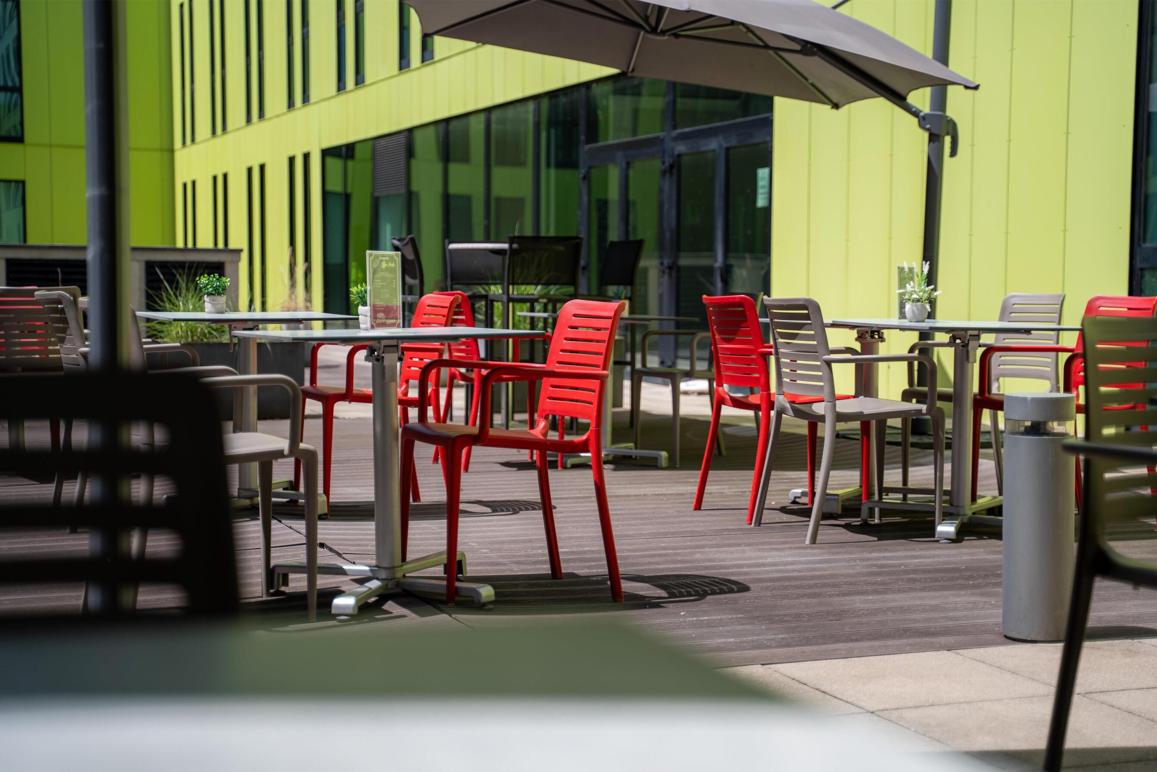 An outdoor seating area with tables and chairs, some with umbrellas.