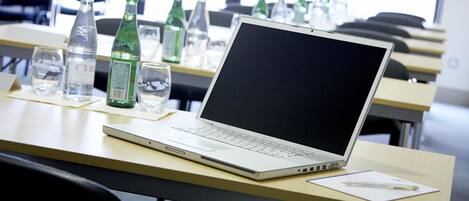 A laptop on a desk with a bottle of water, glasses, and a pen.