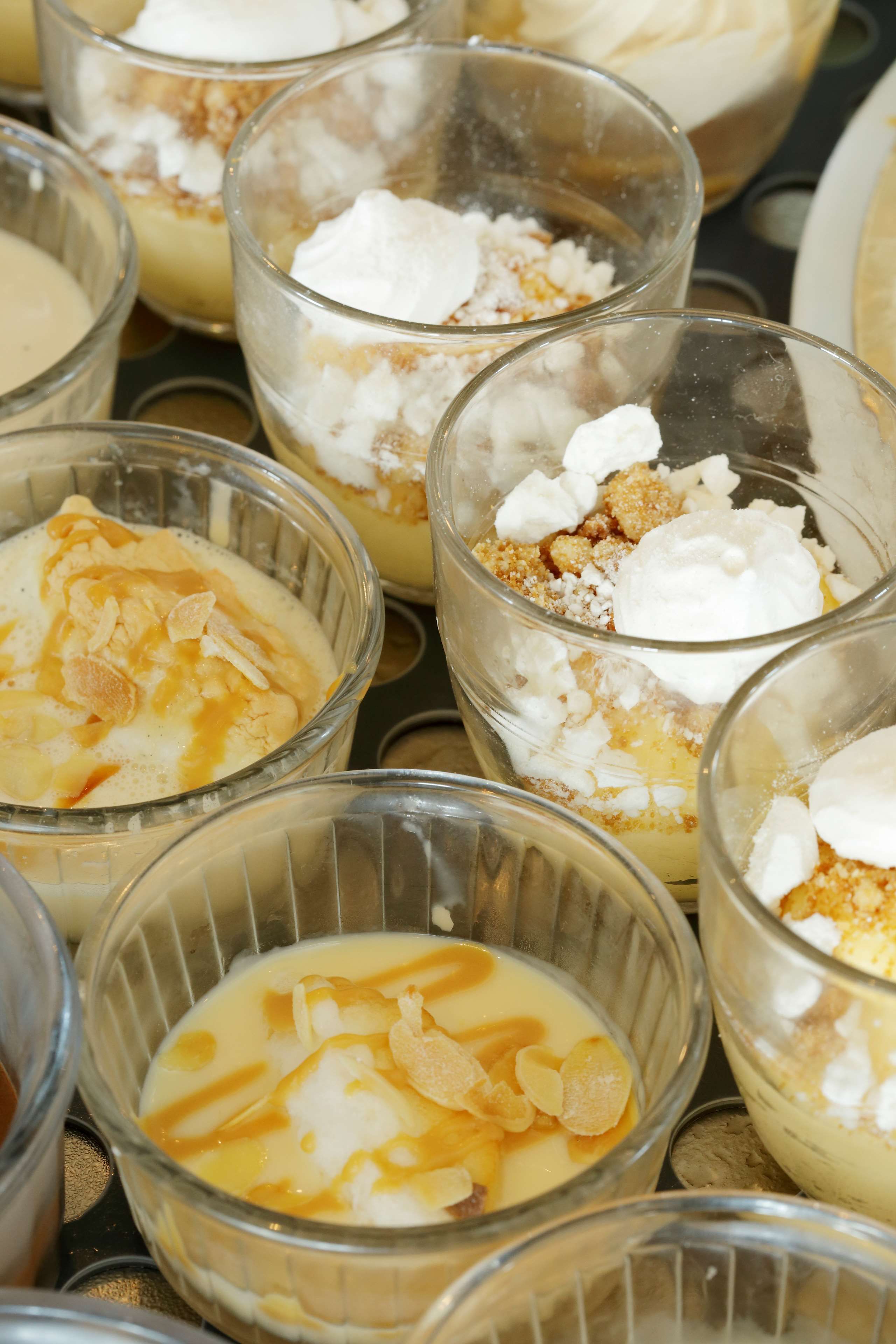 A collection of dessert bowls with creamy bases, topped with whipped cream and caramel.