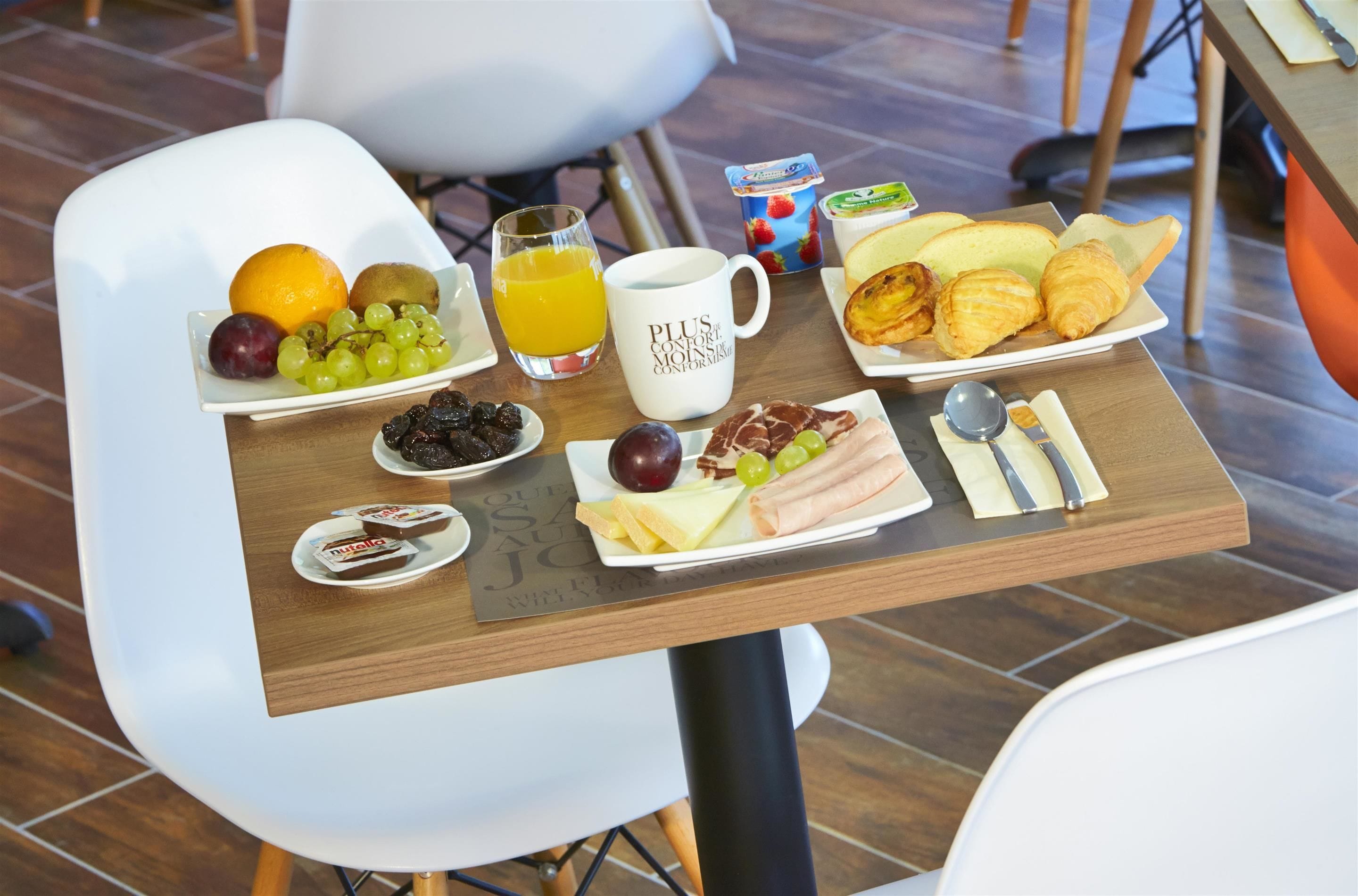 Una mesa de desayuno con diversas opciones de comida, como frutas, pan y pasteles.