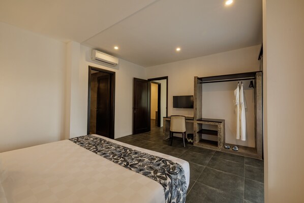 A hotel room with a bed, a desk, a chair, a TV, and a wardrobe.