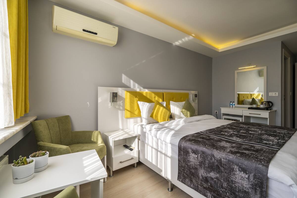 Une chambre d’hôtel moderne équipée d’un lit, d’une table de chevet et d’un bureau avec une chaise.