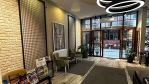 A modern lobby with a brick wall, a large window, and a reception desk. - Sayeban Gold Hotel (Istanbul)
