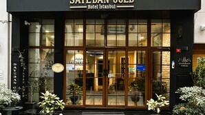The exterior of the Sayeban Gold Hotel Istanbul, featuring a black facade, large glass windows, and potted plants on the sidewalk. - Sayeban Gold Hotel (Istanbul)