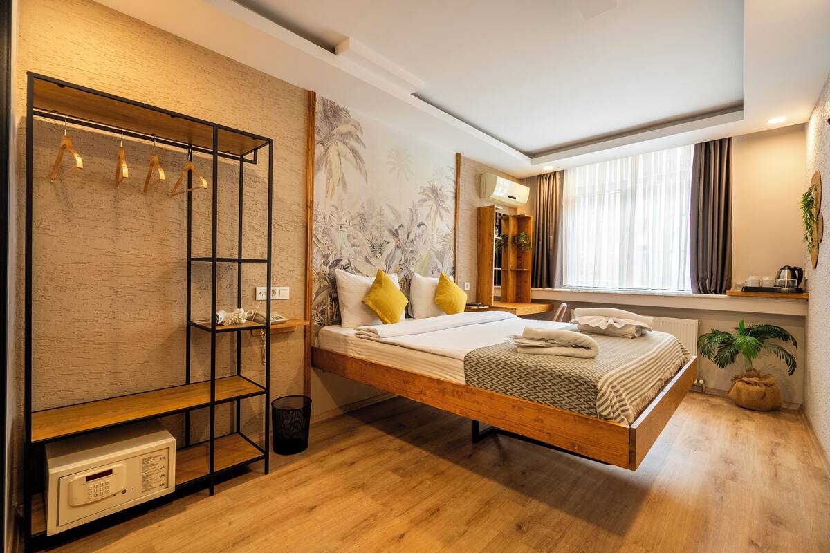 Une chambre moderne avec un lit en bois, une armoire intégrée, une grande fenêtre avec des rideaux et un climatiseur fixé au mur.