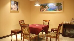 Un comedor con mantel rojo, sillas de madera y dos cuadros en las paredes.