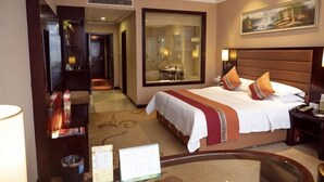 Una habitación de hotel con una cama grande, una mesita de noche, un escritorio y un espejo amplio.