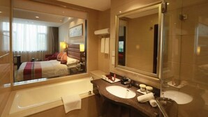 Un baño de hotel con un espejo grande, una bañera, un lavabo y una ducha.