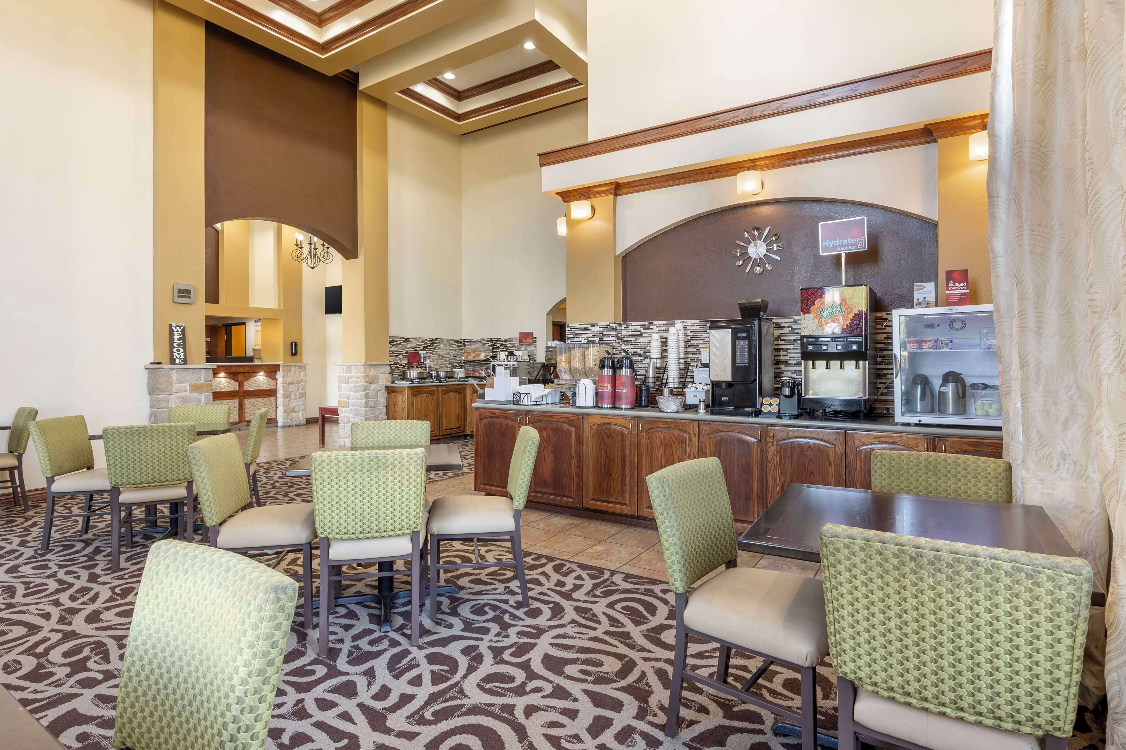 Un vestíbulo de hotel con una recepción, un reloj y una zona de café.