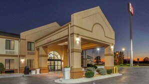 A hotel with a covered entrance, a sign indicating a restaurant, and a well-lit parking area.
