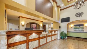 A reception area with a wooden reception desk, a large painting on the wall, and a potted plant.