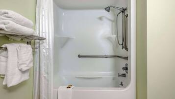 A bathroom with a bathtub, grab bars, and a towel rack with towels.