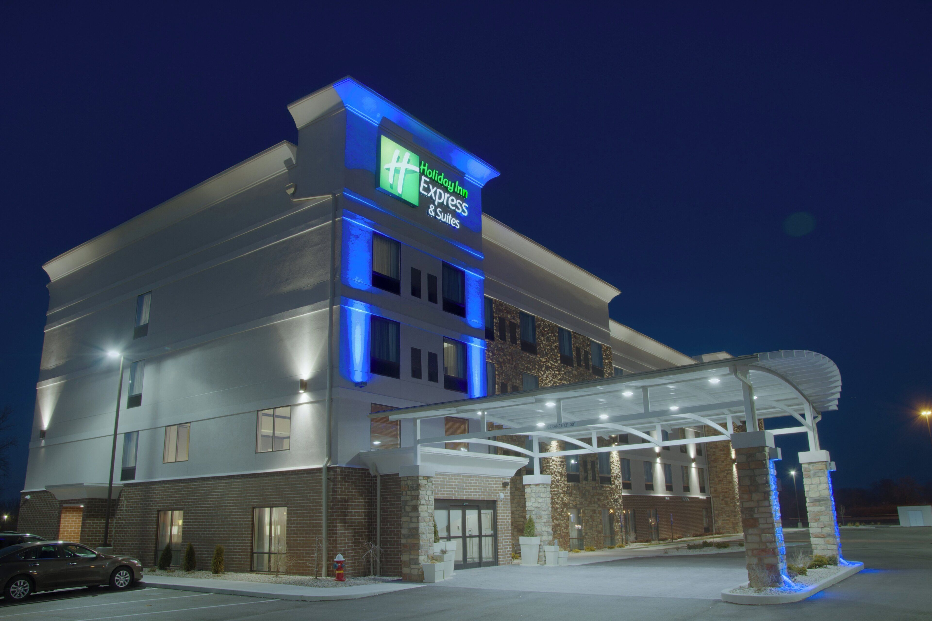 Un hotel Holiday Inn Express & Suites con entrada techada y estacionamiento.