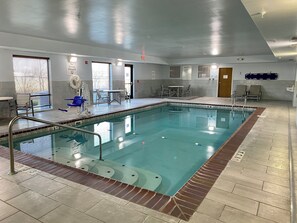 An indoor swimming pool with a tiled floor, a pool ladder, and a seating area with chairs and a table. - Holiday Inn Express & Suites Sidney by IHG (Sidney)