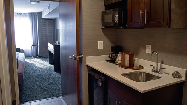 Een hotelkamer met een kitchenette, inclusief een magnetron, spoelbak en kastjes.