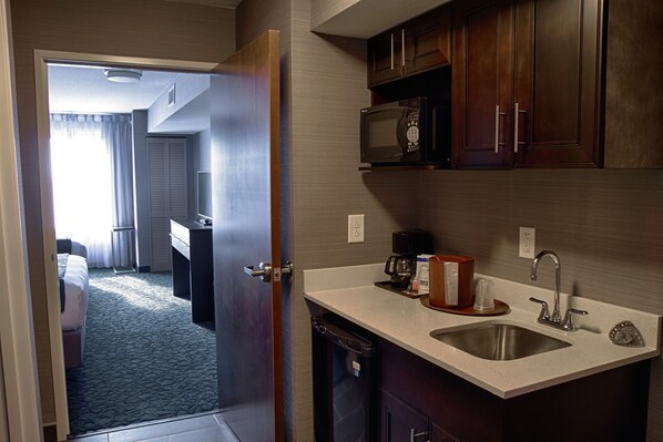 A hotel room with a kitchenette, including a microwave, sink, and cabinets. - Holiday Inn Express & Suites Sidney by IHG (Sidney)