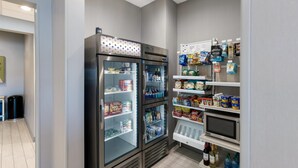 Una cucina moderna con due frigoriferi, un forno a microonde e scaffali pieni di snack e bevande.