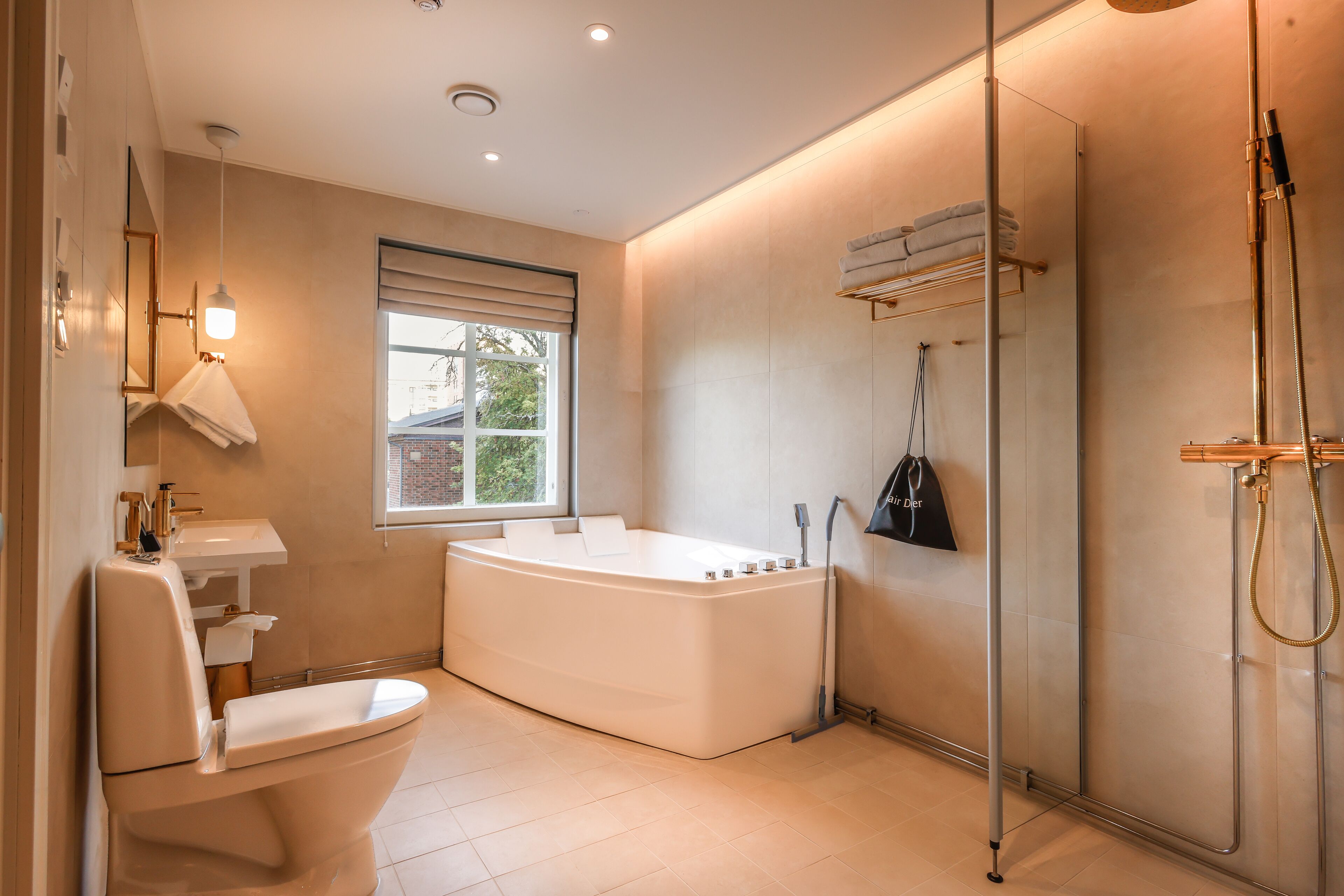 A modern bathroom with a freestanding bathtub, a toilet, a sink, and a shower area.