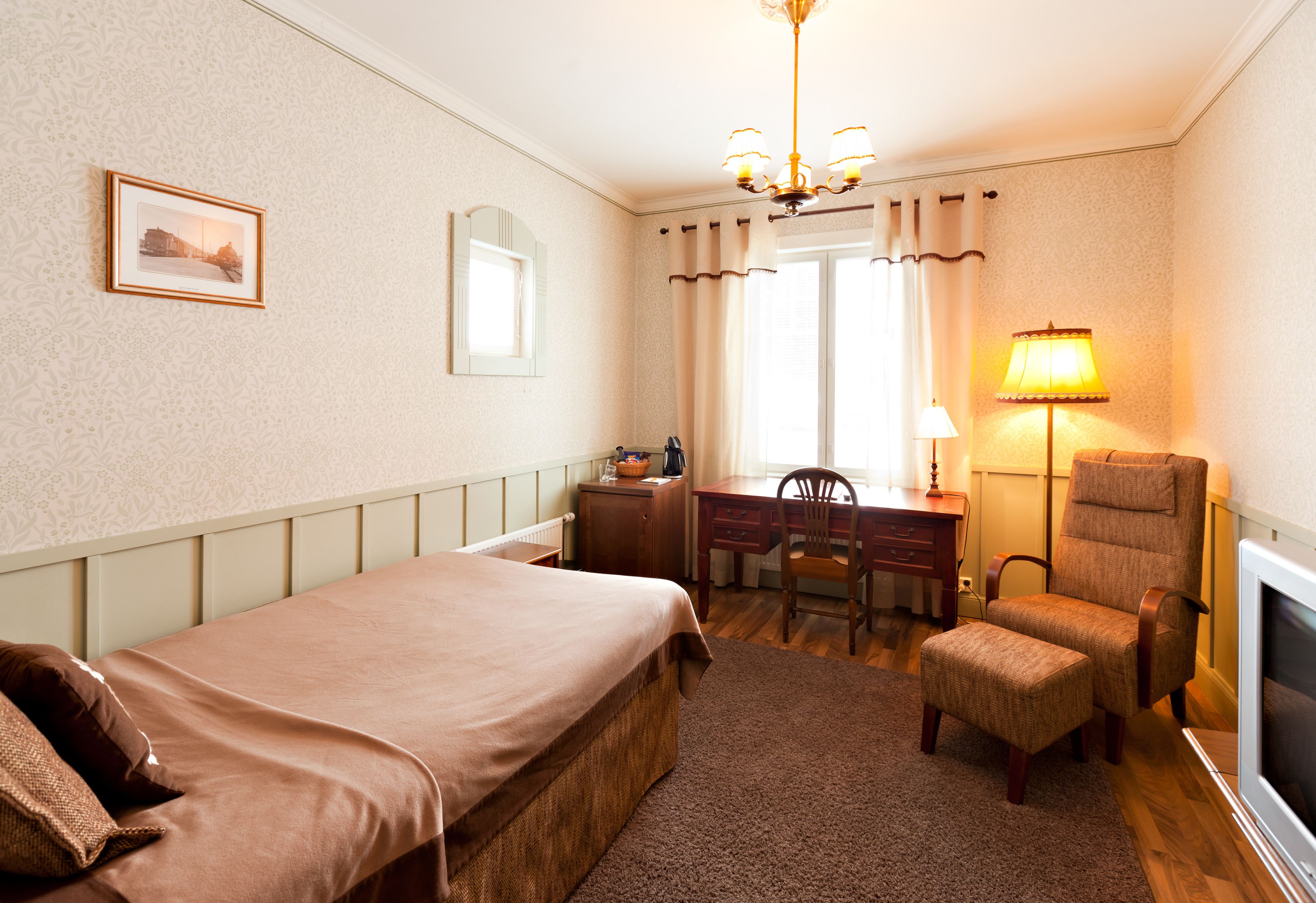 A hotel room with a bed, desk, chair, and TV.