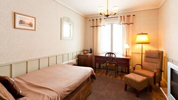 A hotel room with a bed, desk, chair, and TV.