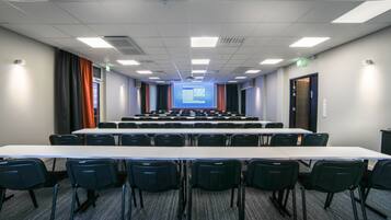 A conference room with a long table and chairs, a projector screen, and a presentation slide.