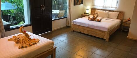 A hotel room with two beds, a large window, and a view of greenery outside.